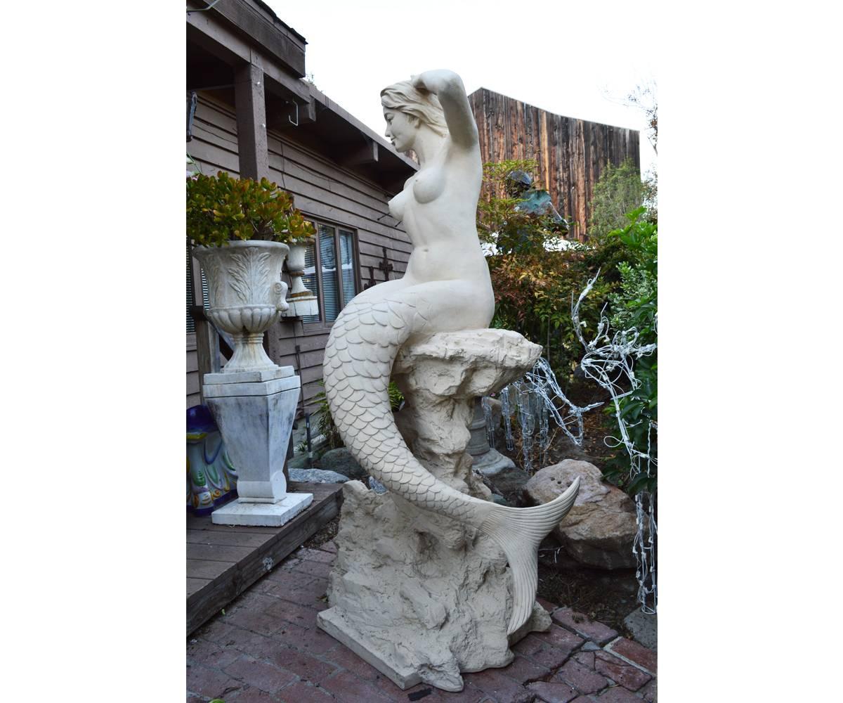 Offered is this large and very lifelike mermaid statue with the subject resting upon a marine rock like pedestal. The detail on this item is incredible and would a tremendous addition to any pool, pond or garden area.