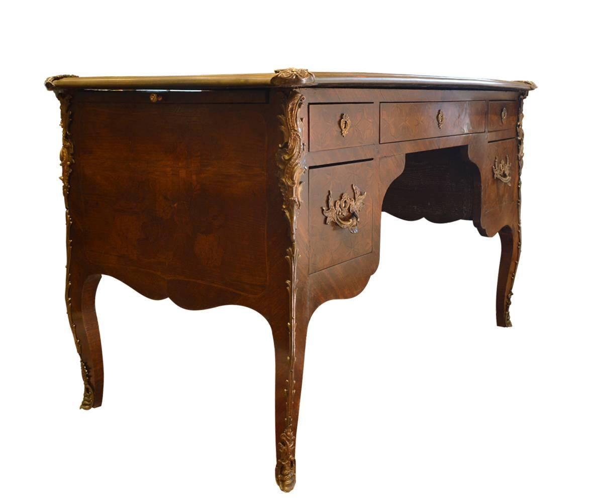 This wonderful French Antique writing desk has the original leather writing surface and is wonderfully decorated with ormolu accents and pulls along with beautiful marquetry work. This is a smaller "petite" adult size.
