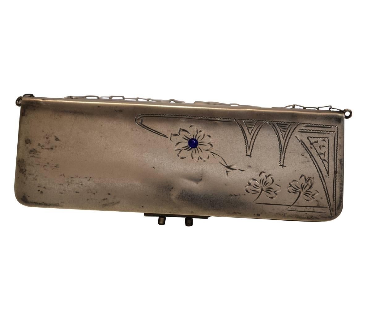 This purse has three compartments, one with a mirror. The sterling is etched with a foliage design and the center of one of the flowers has a sapphire.