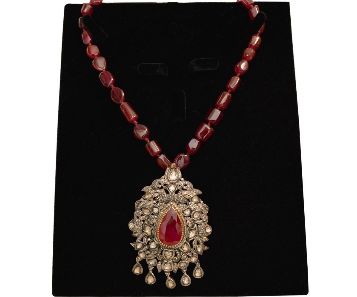 One electronically tested silver and gold ladies custom cast and handcrafted ruby and diamond pendant with necklace and a bright finish. The 24" length necklace features a ruby and diamond ornament supported by a flexible ribbon of rubies