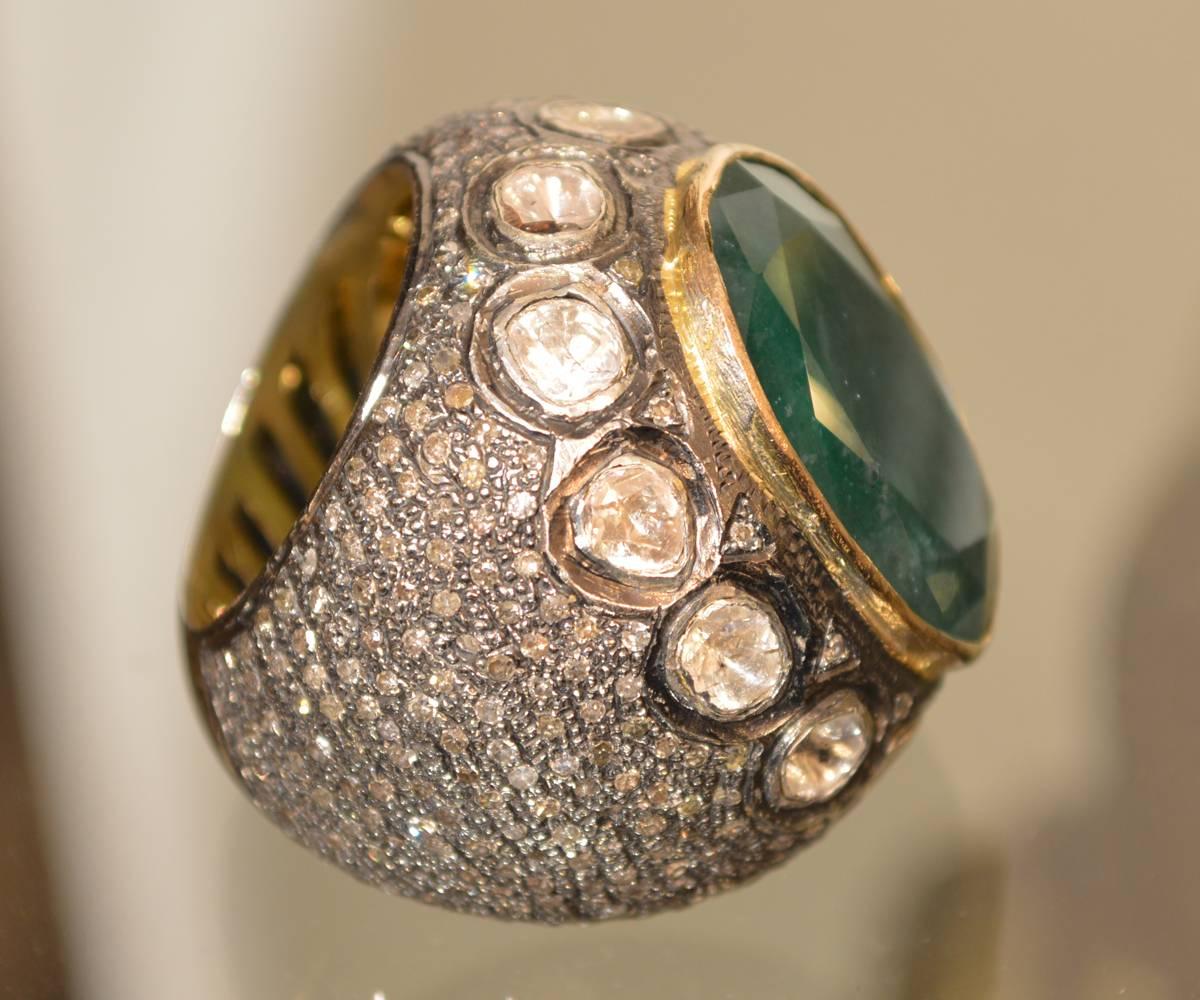 One electronically tested silver and gold ladies custom cast and had crafted emerald and diamond ring. The featured emerald is set within a yellow gold bezel and diamond frame, supported by diamond set shoulders and completed by an eleven millimeter