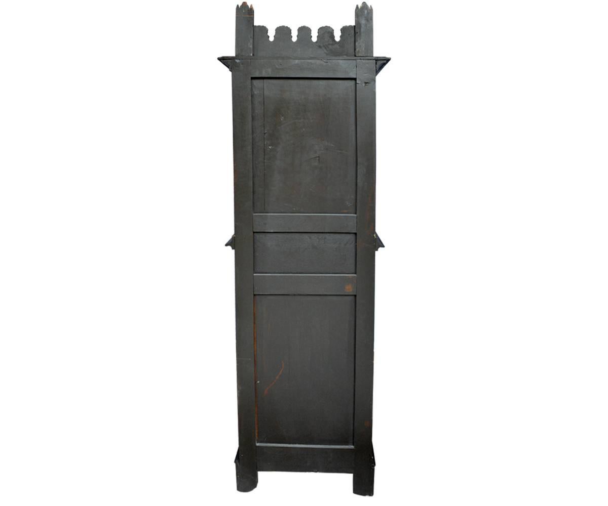This is an antique Gothic style small cabinet with a dark finish and gold accents. Unusual in this style of cabinet is the extra detailing on the side panels. Also lending to the quality of this piece is the additional crown which is rarely found on