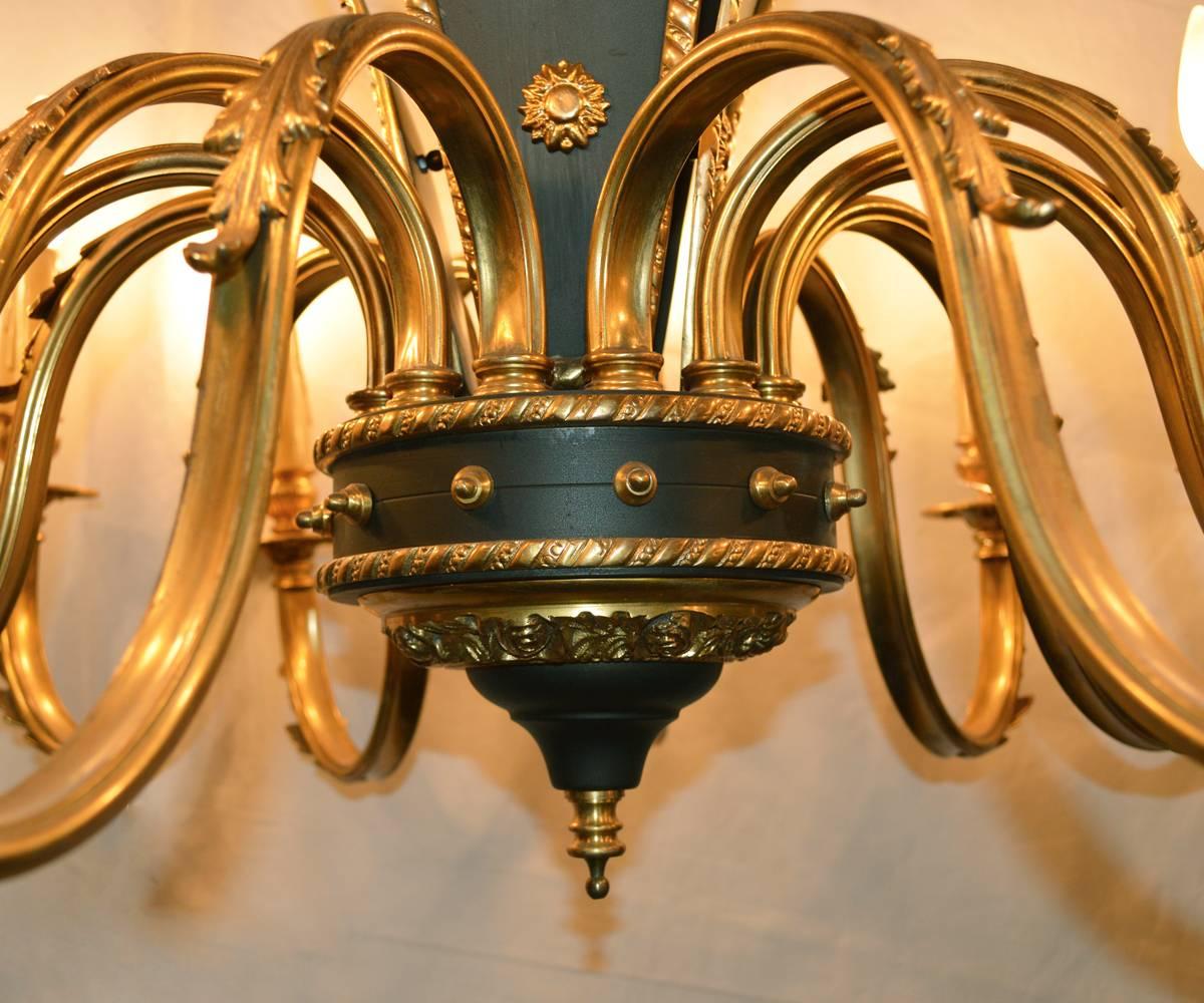 This midcentury gilt bronze chandelier has twelve arms, unusually all onone level, has hand-painted black to accent the gilt work. This chandelier change off significant light or be toned down with less wattage or dimmers.