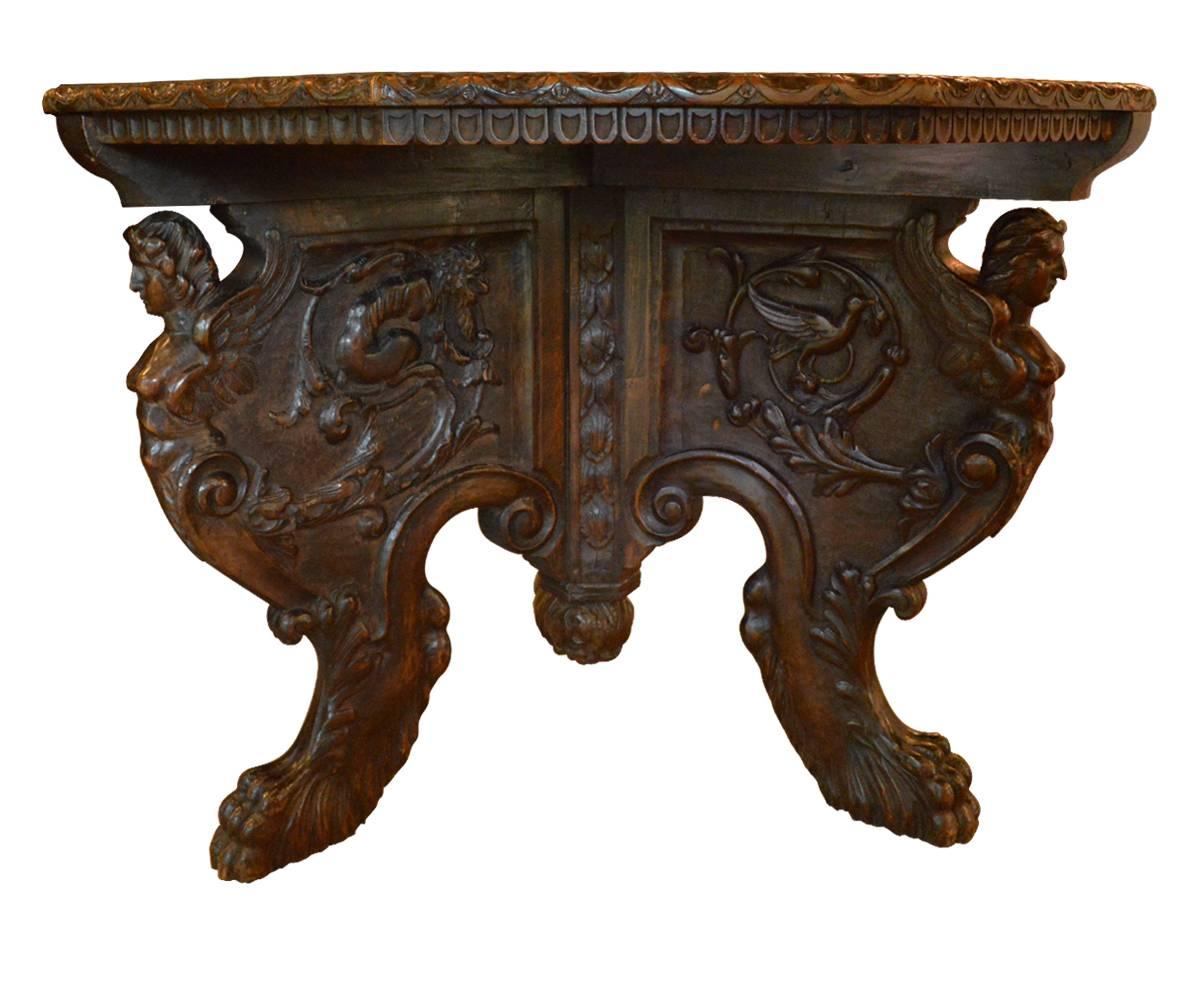 This incredible table has all the elements one looks for in an exceptional example of fine Renaissance furniture. There are three legs, all with different carvings including female angels, birds, dragons and griffins finishing with lions feet. The