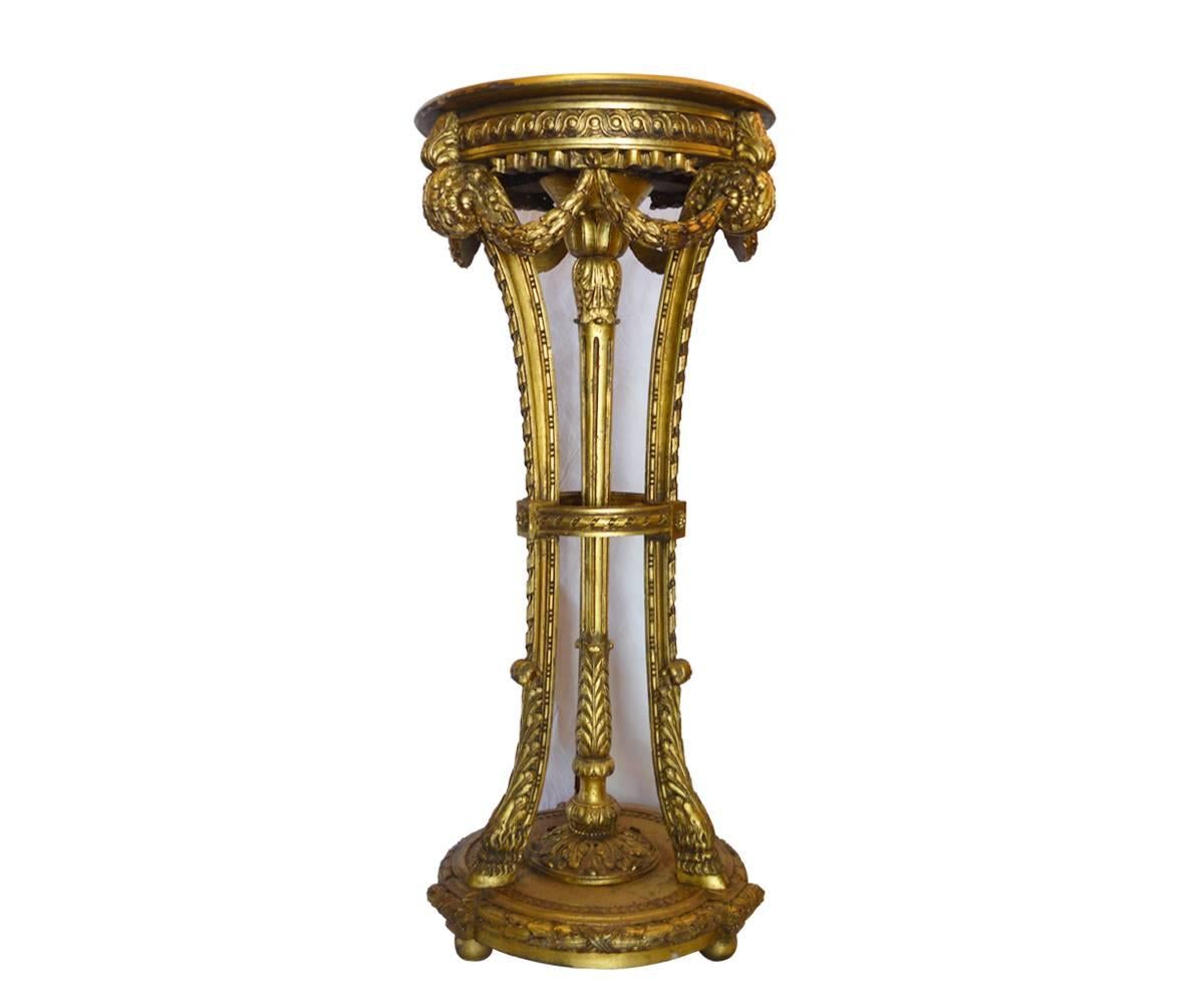 This gorgeous antique tall pedestal has hoofed feet that rest upon a circular base and in decorated with gilt leaves and rosettes.