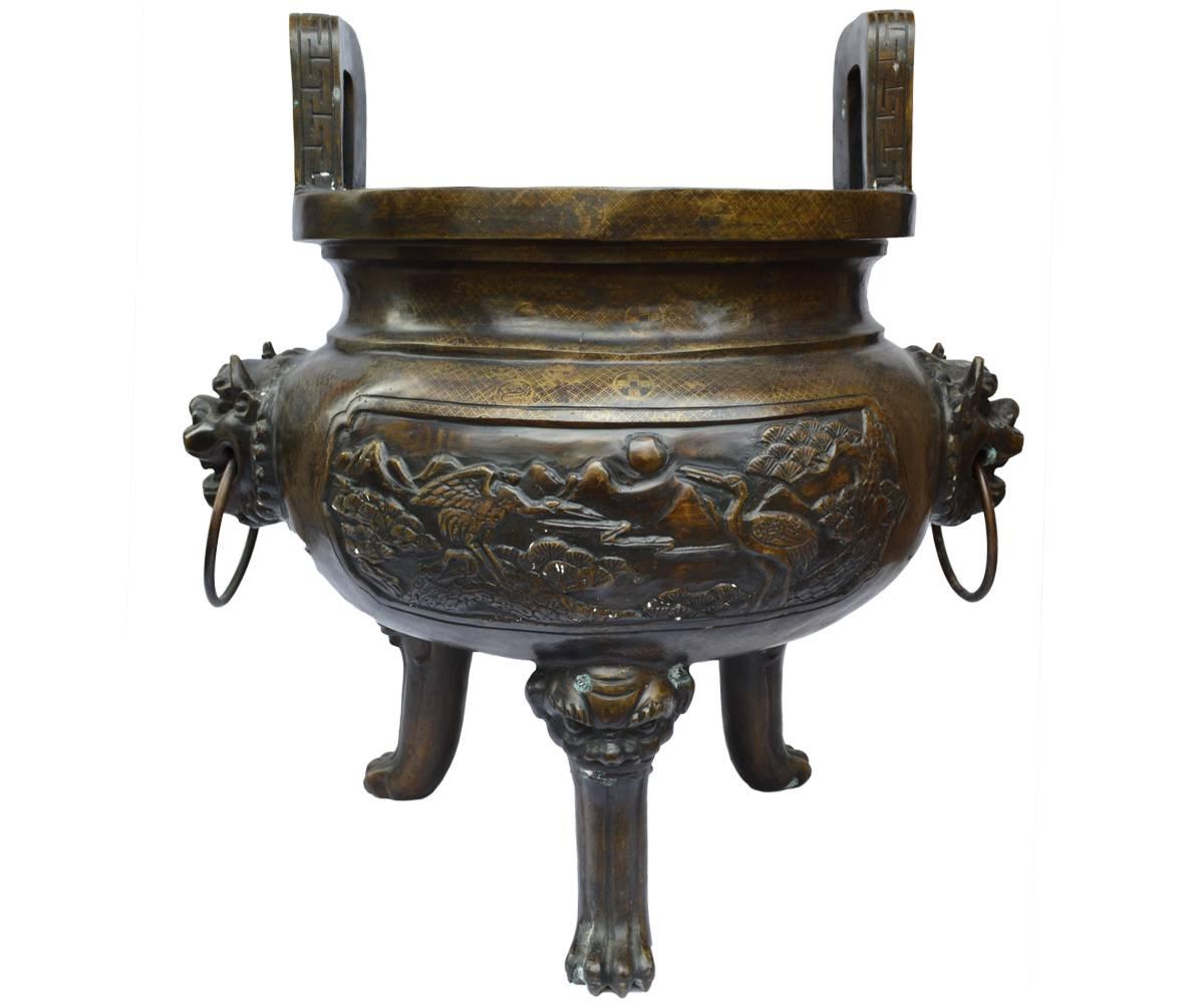 This bronze planter has all of decorative features one could want. It has large rectangular handles upright handles, two lion mask side handles with rings, three paw feet springing forth from lions heads and is decorated with side panels with deer