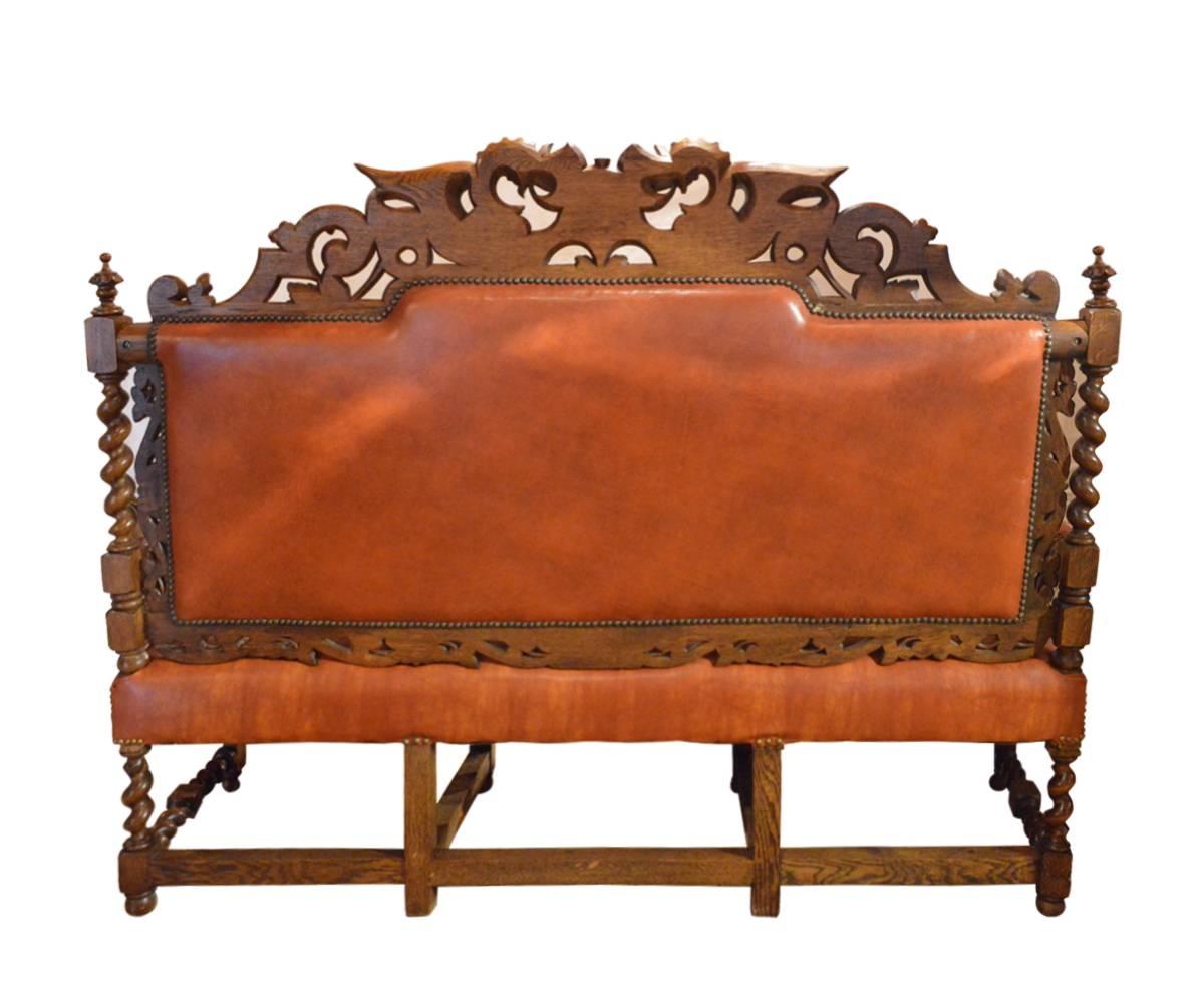This well carved bench has hand-carved flying dragons on either side of a coat of arms. The bench has barley twist legs, arms and stretchers.