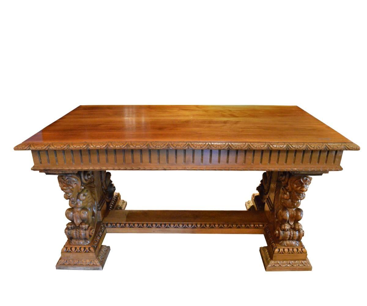This well carved desk features four gargoyles and impressive decorative carvings throughout. This antique can be used as a dining table, center table or desk. It currently has it's original lighter finish. We could darken this table in house with