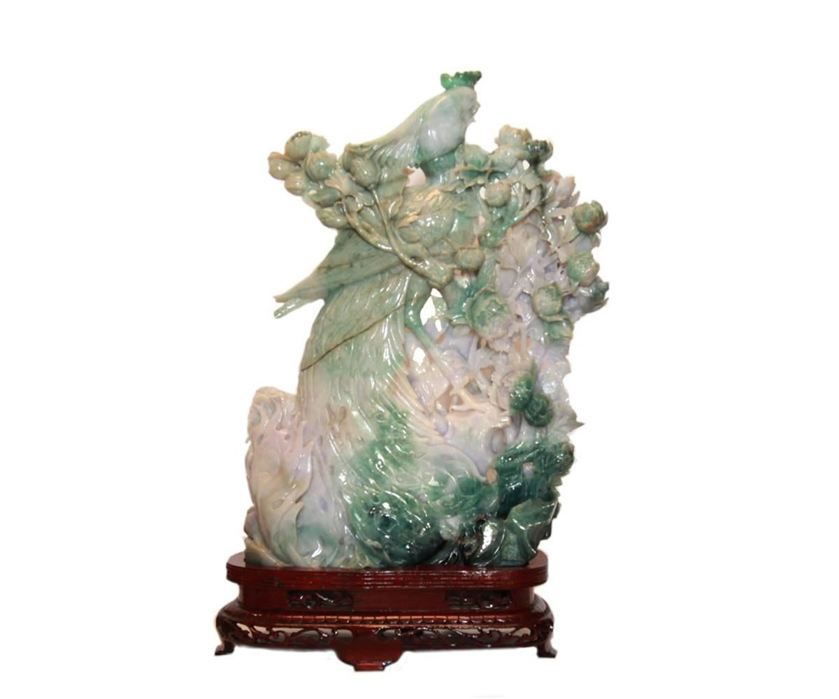 Offered is a rare pair of large and exquisitely openwork carved complementary Chinese jadeite birds. Each one is a phoenix and both are perched amid branches of large peony flowers. The carving is very fine and the jadeite coloration is a