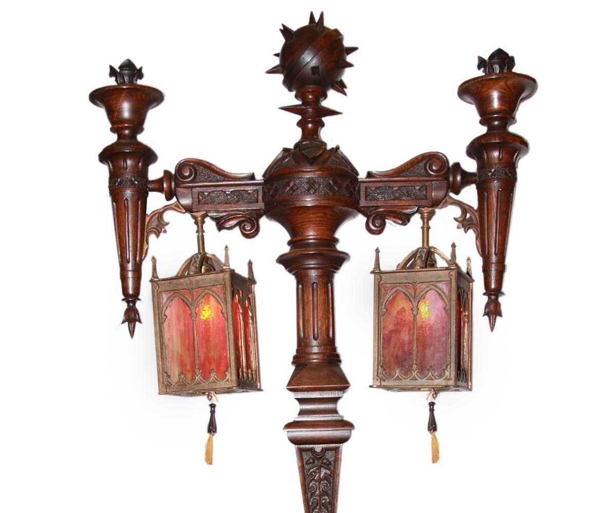 This antique is a sophisticated Gothic oak floor lamp with attached table. Octagonal table top has a twisted carved border on the apron with center post having four carved pilasters with carved support arms above and a crossed base standing on