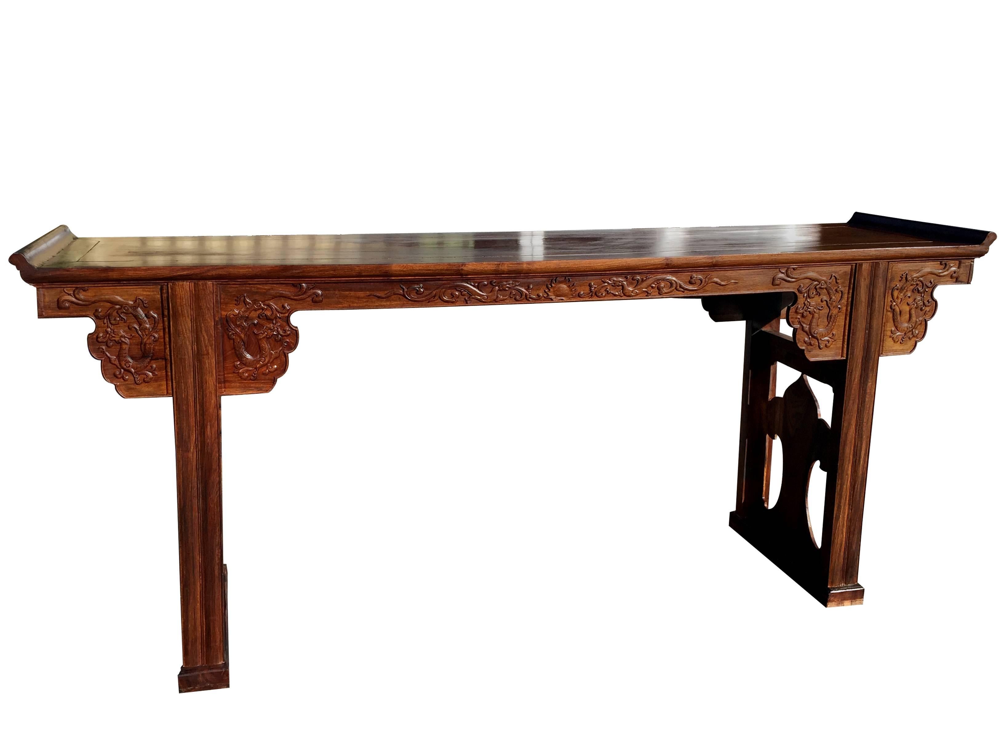 We proudly offer this fine Haunghauli wood altar table. This fine Chinese huanghuali wood altar table is accented with upturned sides. The table is ornamented with carved details of scrolling chilong in relief and boasts cutouts to the two side