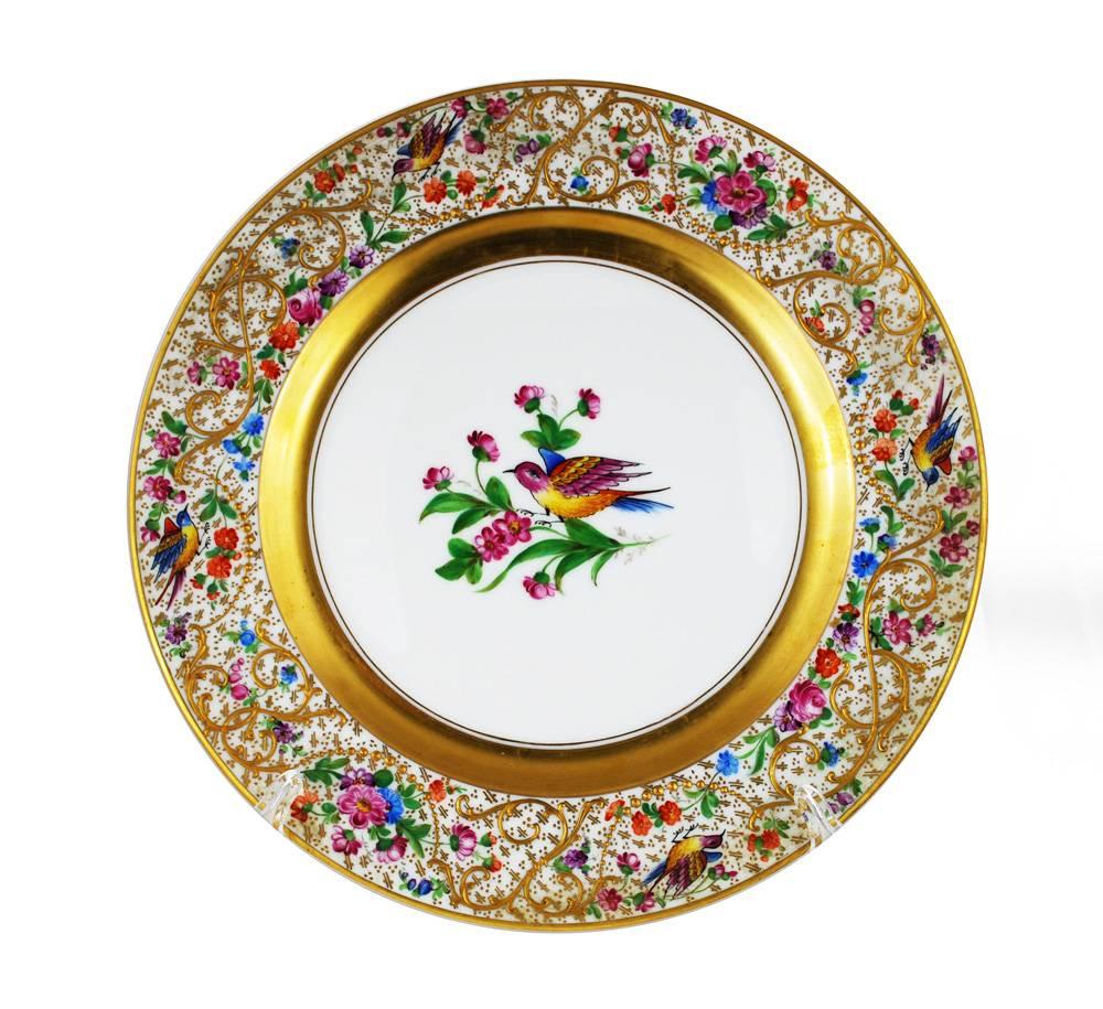 A set of 12 ebullient dinner plates from the famous porcelain studios of Ambrosius Lamm. These hand-painted, nicely gilded plates showcase colorful birds and a profusion of flowers set amongst elaborate gilt paste scroll work and raised beading. The