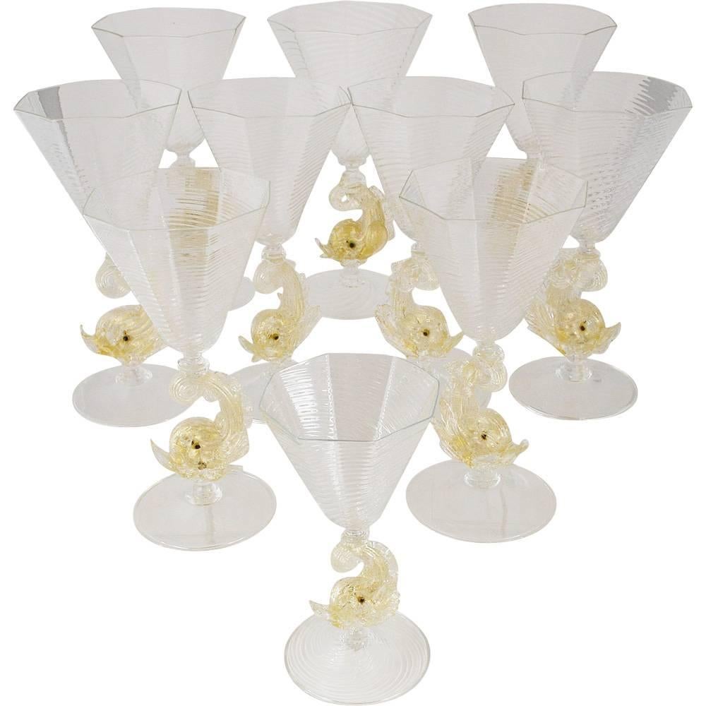 A marvelous set of eight handblown Venetian glass Murano goblets with ornate dolphin stems. Clear glass with octagonal shaped bowls showcase a phenomenal spiral design radiating outward. Classic gold flecked dolphin stems and round clear glass