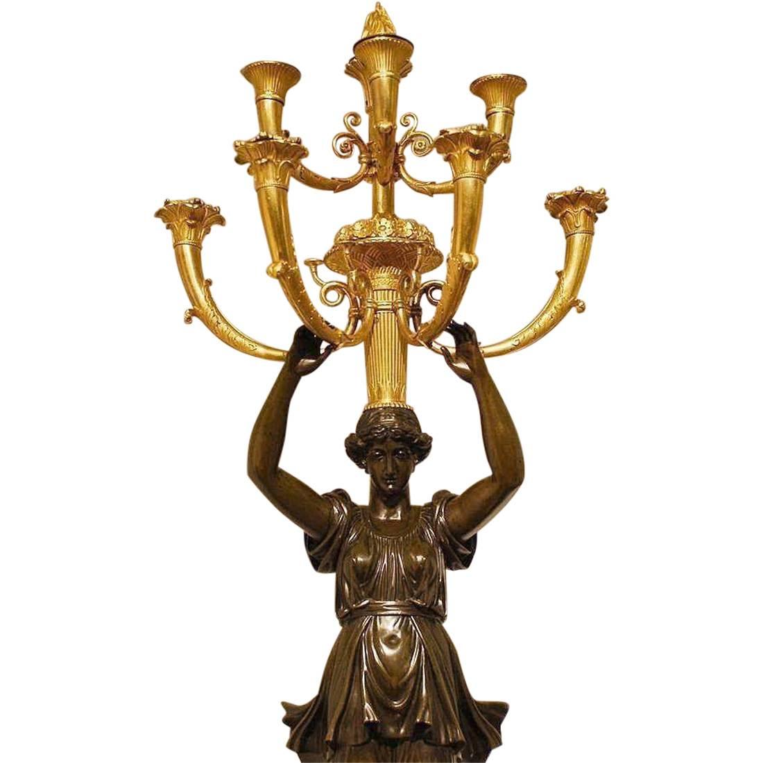 Important French Empire ormolu and patinated bronze palace sized candelabra from the early 19th century, one of a few known to exist. 

The plinth is solid Rouge Royal Marble on a gilt bronze base. Mounted on all sides are detailed ormolu reliefs,