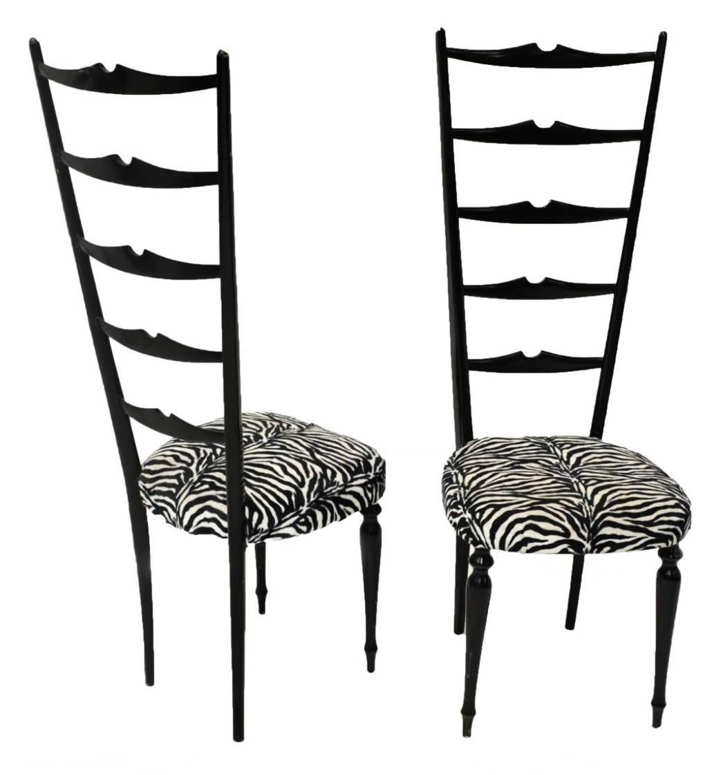 Stylish pair of Chiavari high back chairs in glossy black. Flared ladder back with notched slats. The front legs are dainty turned balusters. These chairs make fantastic accent pieces. The top reaches four feet high, the seat is a standard 18 inch