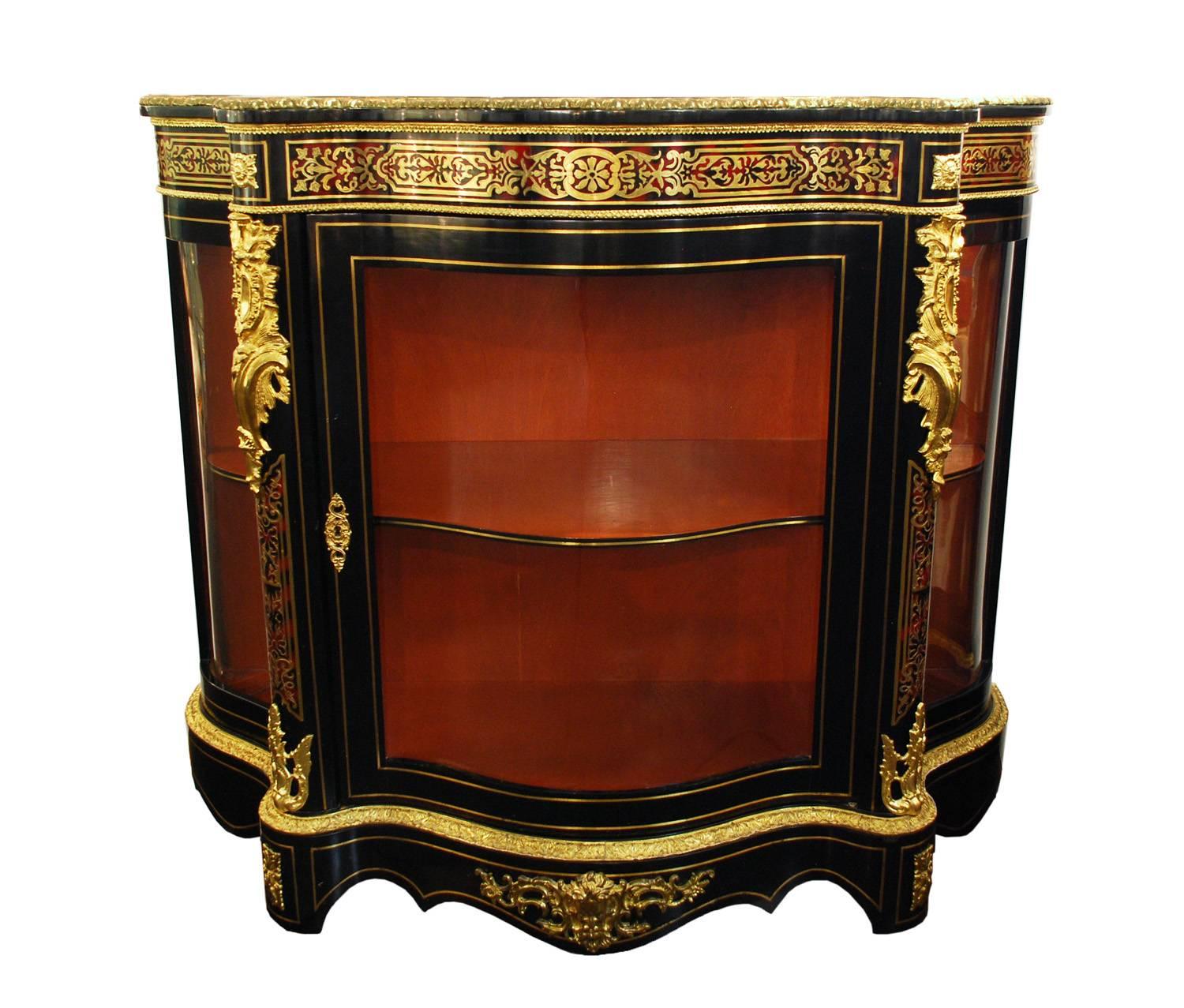 Impressive pair of Boulle style ebonized cabinets with glass doors and copious adornment. The tortoiseshell type inlay and intricately cut brass bands grace the top and sides of each piece. Brilliant brass molded edging and banded inlay trace the