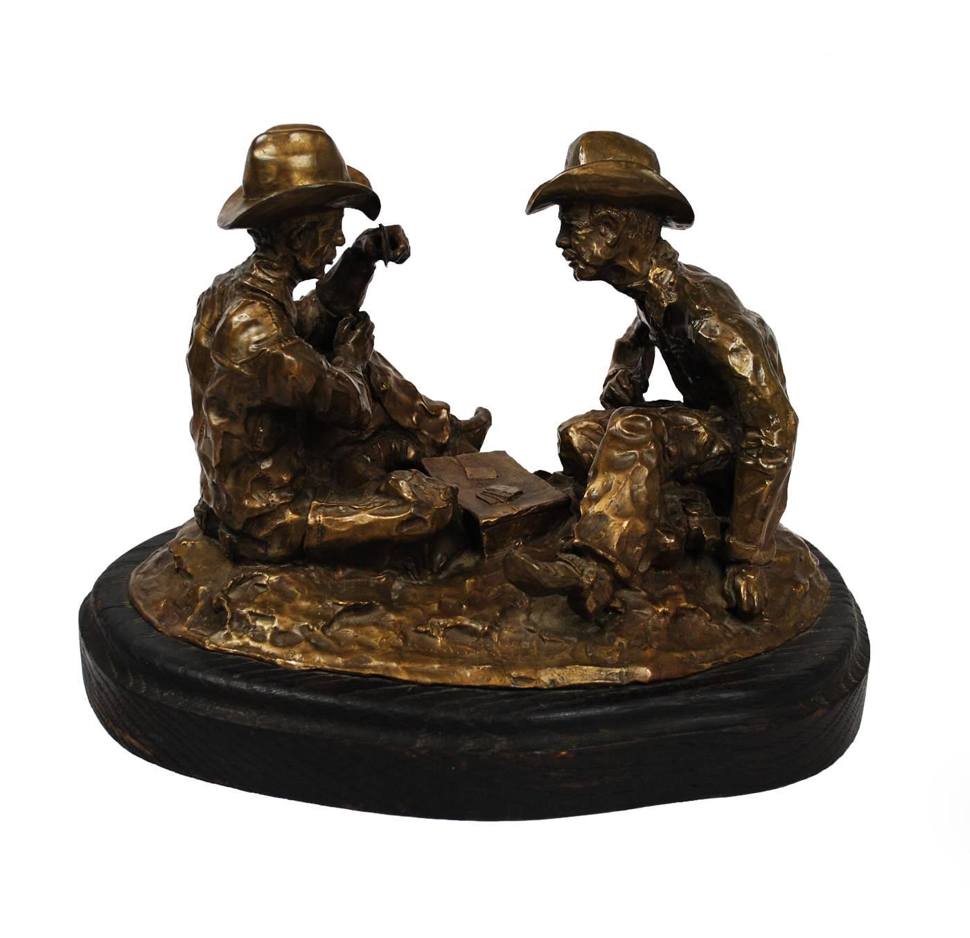 A western themed cast bronze sculpture by artist Jim Thomas. Two cowboys sit together playing a high-stakes hand in poker. Rustic execution matches the subject matter. The piece is marked in bronze 