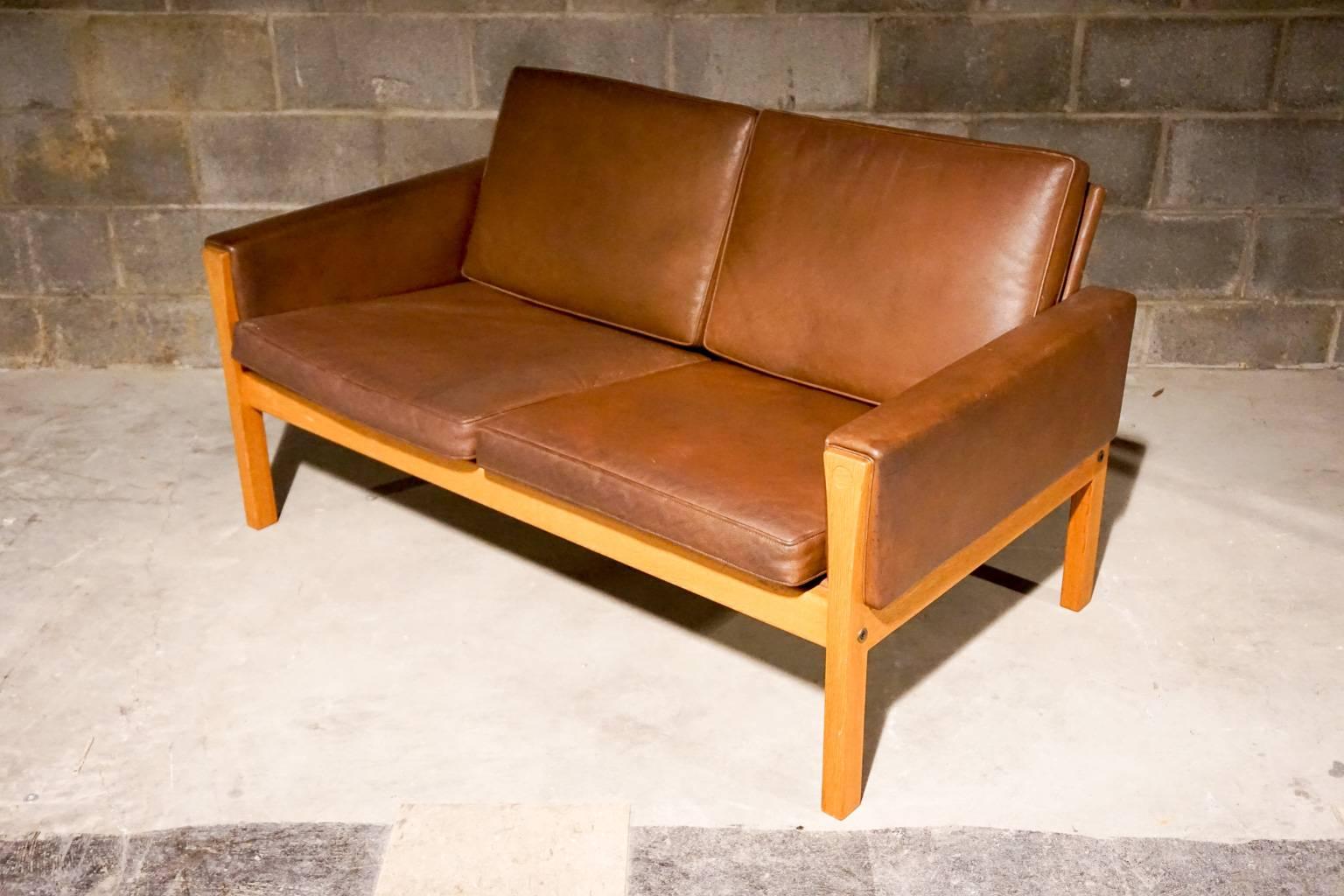 Hans Wegner two-seat sofa, model CH 162. Thick brown leather and oak frame. Superb quality.