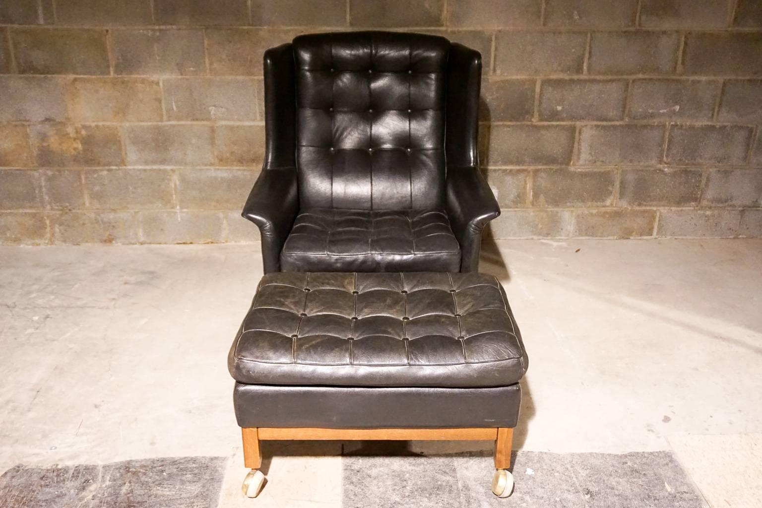 Arne Norell lounge chair in black tufted leather with foot stool. Black tufted leather.

Stool:- H-16 x W-28 x D-21.