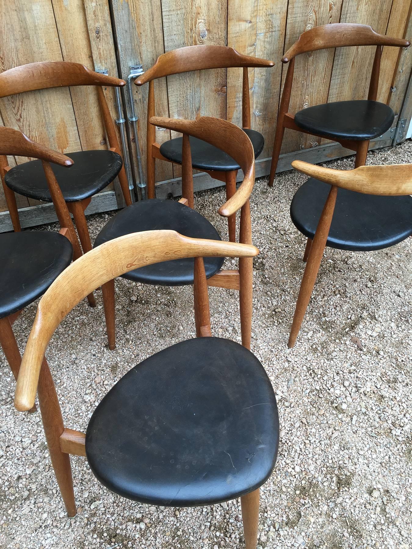 Rare set of eight dining chairs designed by Hans Wegner, model- the Heart chair. Manufactured by Fritz Hansen. Three-legged oak frames with original black leather seats. Nice wear and patina.