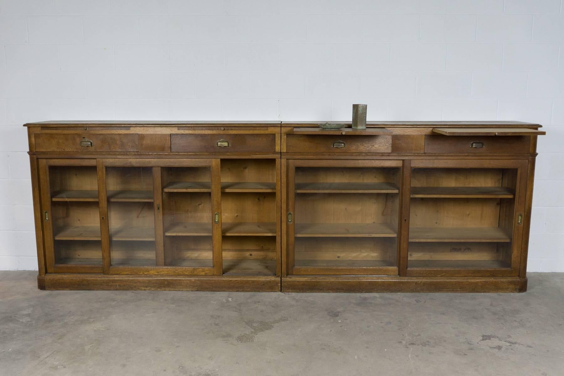 French apothecary cabinet in oak. Sliding glass doors, with drawers and pull-out shelves. Two pieces with adjustable shelving.