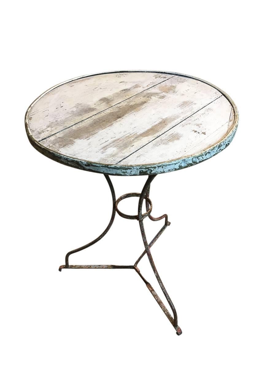 French bistro table. Brass rim on a painted wood top with a metal base. Nice wear.