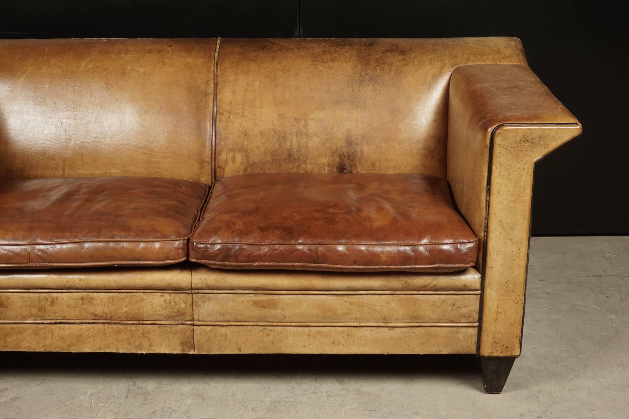 Rare Midcentury Leather Sofa With Profiled Arms and Feet.  Cognac leather upholstery.  Feet covered with black leather.