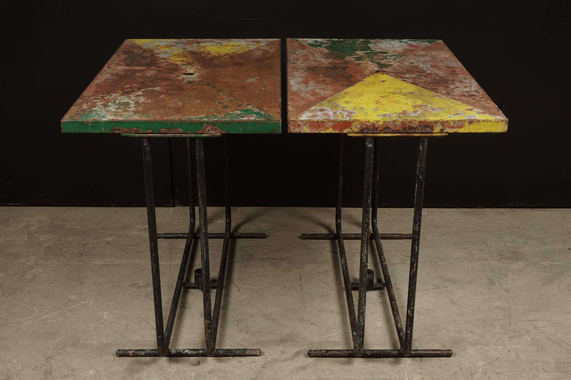 Pair of French Bistro Tables in original paint, circa 1940.  Fantastic color and patina.  Clamp on base for an umbrella.