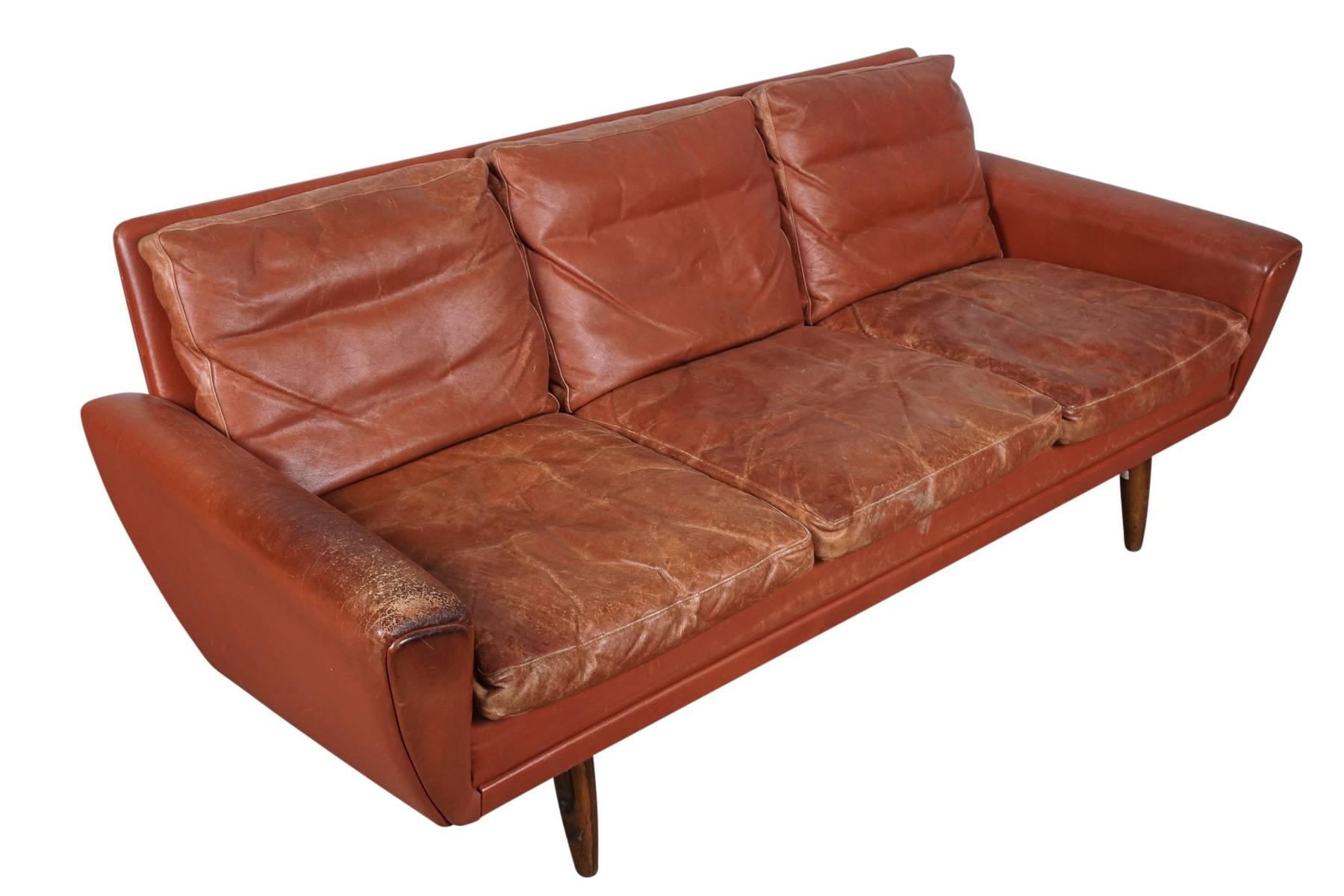 Danish Mid-Century sofa in red leather with nice wear and patina. Designed by Georg Thams, Denmark. Down filled cushions and tapered rosewood legs.