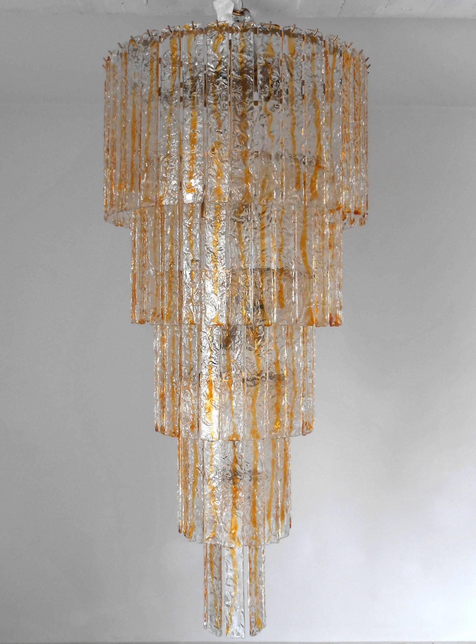 Vintage Italian chandelier with clear and amber Murano textured glass planks, mounted on brass frame / Designed by Mazzega circa 1960’s / Made in Italy 
16 lights / E26 or E27 type / max 60W each
Diameter: 28 inches / Height: 60 inches plus chain