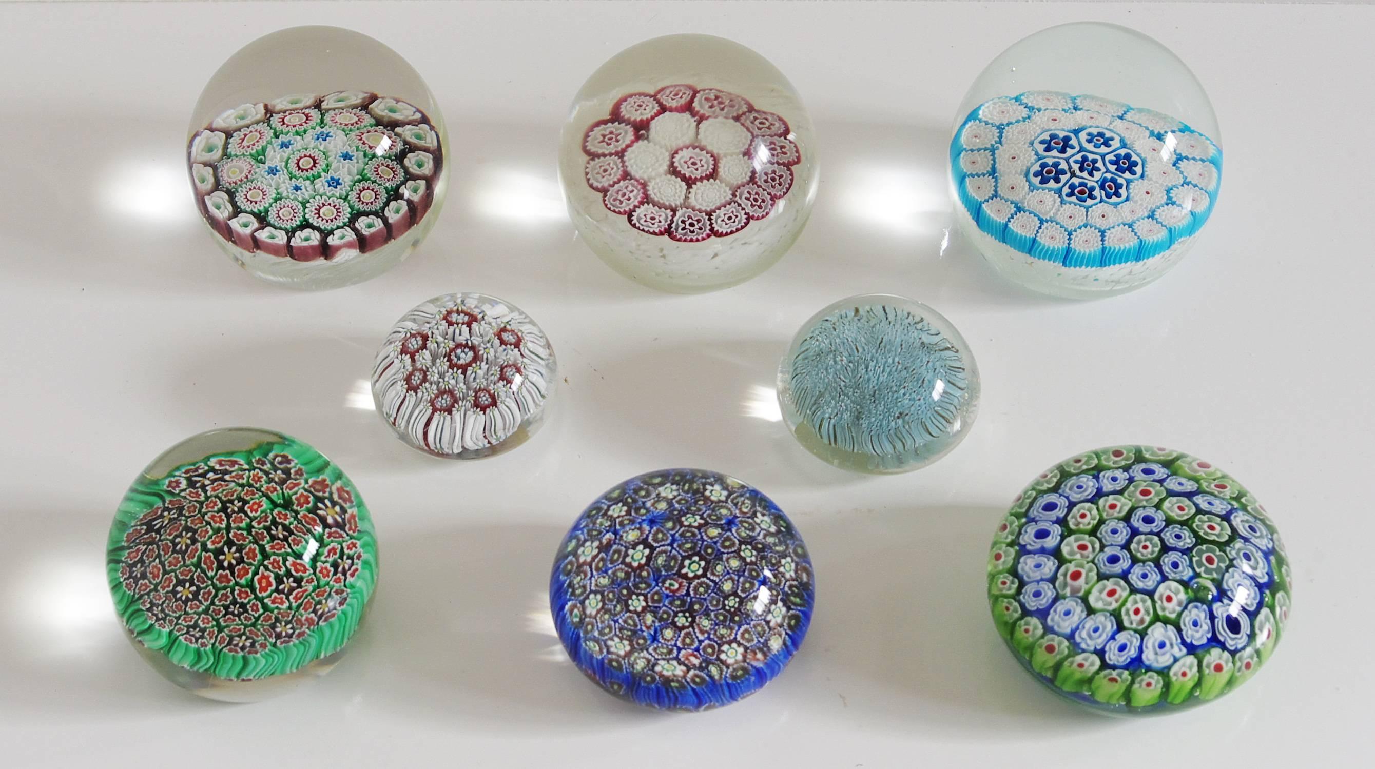 Collection of eight paperweights  made with clear, blue, green, and red Murano glass hand blown in beautiful Millefiori (a thousand flowers) pattern. Four of the eight paperweights have original stickers / Made in Italy in the 1960's
Diameter for