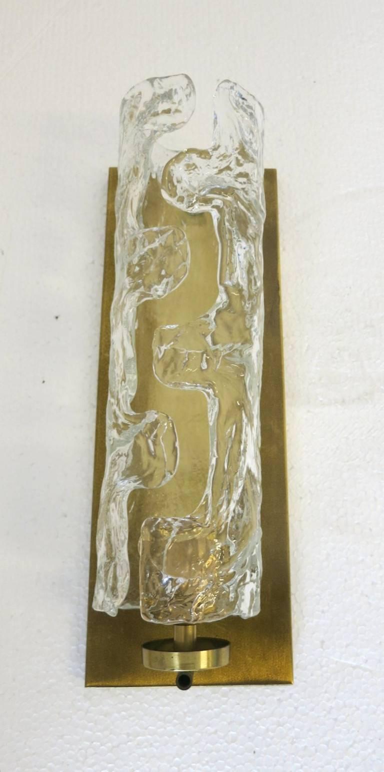Vintage Italian wall light with clear Murano glass hand blown to create textured fluid elements in an open cylindrical shape, mounted on rectangular brass back plate / Designed by Mazzega, circa 1960s / Made in Italy
1 light / E26 or E27 type / max