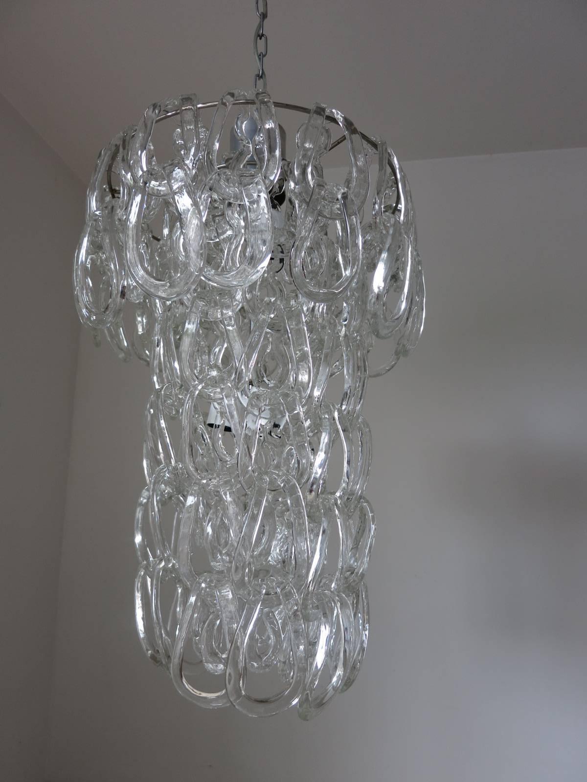Vintage Italian chandelier with hand blown clear Murano glass links, elegantly fitted on chrome frame and descending into a glass chain / Designed by Angelo Mangiarotti for Vistosi circa 1960’s / Made in Italy
4 lights / E26 or E27 type / max 60W