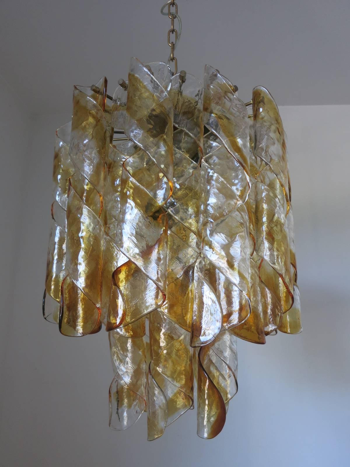 Vintage Italian chandelier with 32 clear and amber infused Murano glasses blown into twisted spiral shapes, mounted on brass metal frame / Designed by Mazzega circa 1960’s / Made in Italy 
7 lights / E26 or E27 type / max 60W each
Diameter: 18