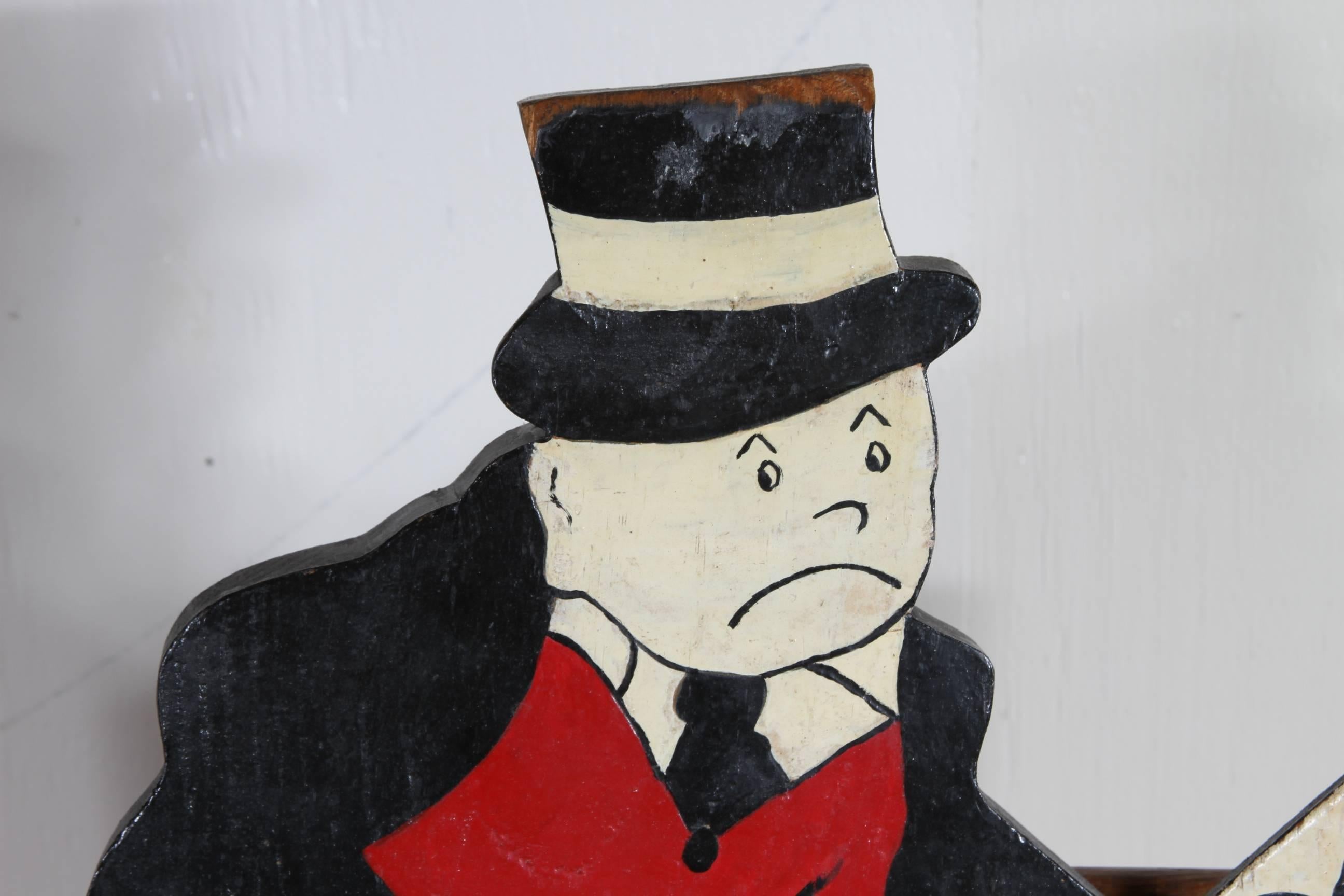 Slats, possibly from a sign, are attached to the back and under the seat. The character resembles the main character from the Monopoly board game, dressed in black and red with a top hat, cane and suit with vest.