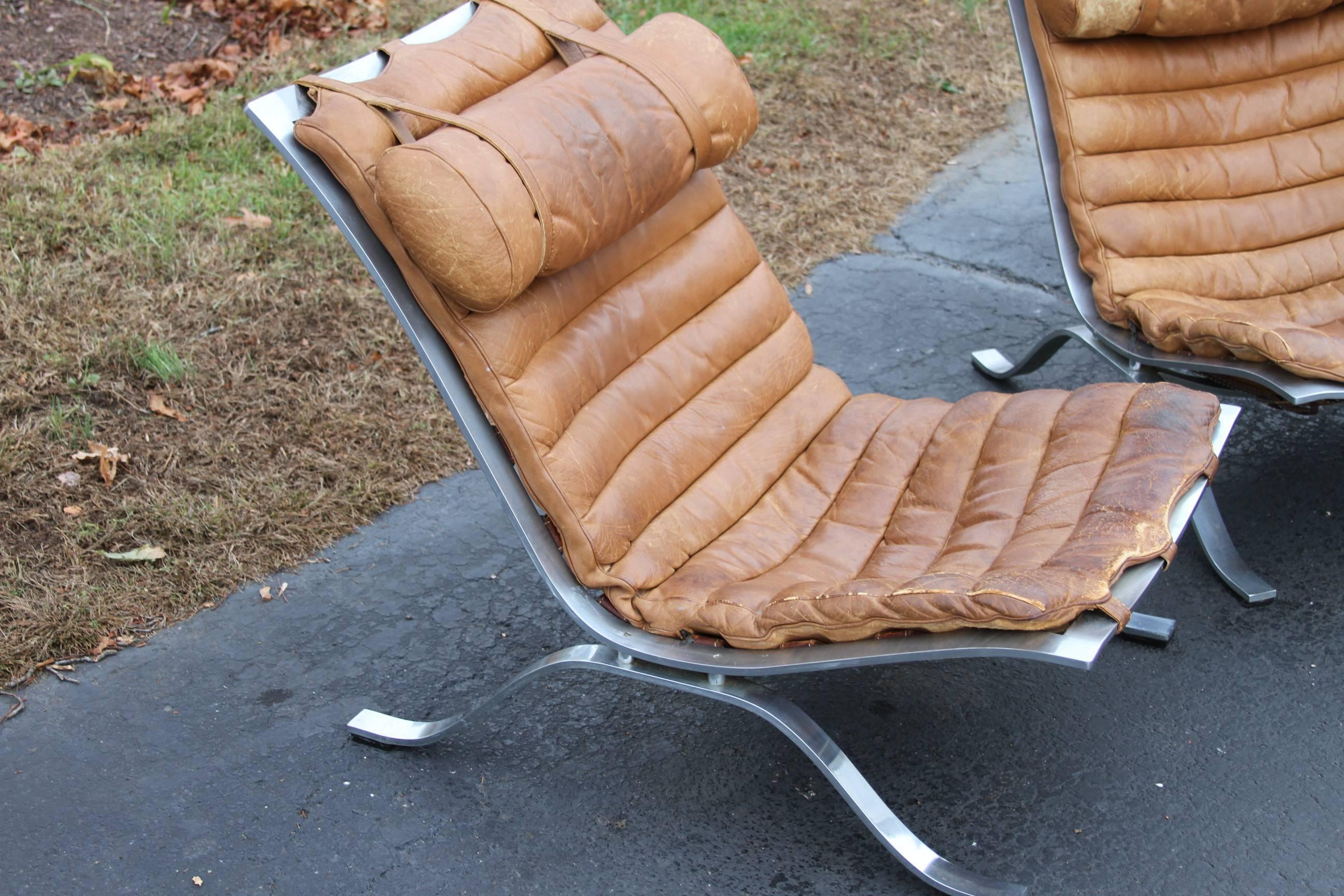 Spectacular pair of Ari easy chairs designed by Arne Norell in 1966 and manufactured by his company in Aneby, Sweden. As comfortable and sturdy as they are comfortable, the original brown leather is very worn and soft, with some slight staining. An