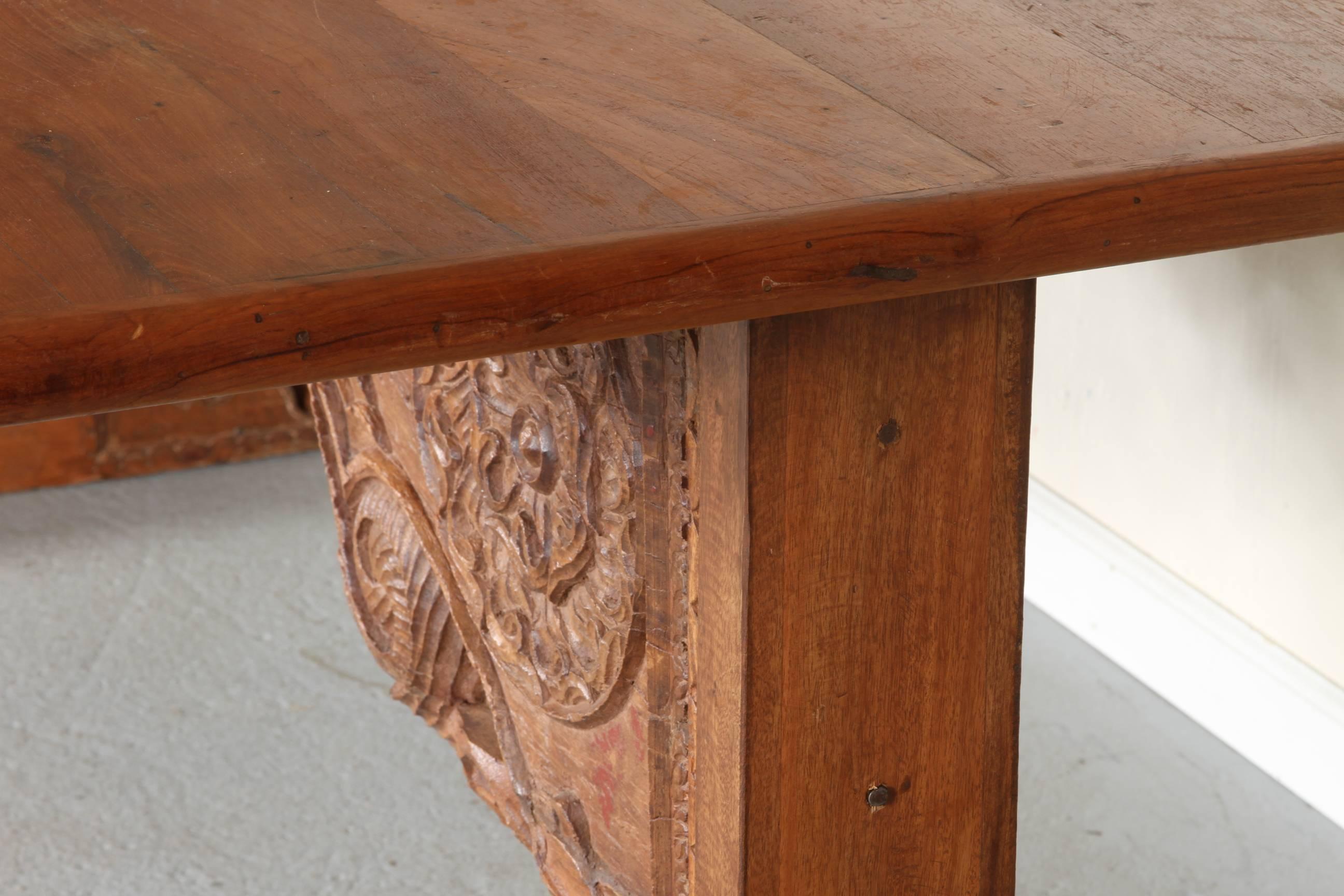 Une belle grande table à tréteaux en bois dur indien. Les supports massifs des tréteaux, ainsi que le brancard, sont des éléments architecturaux anciens incorporés avec un design traditionnel sculpté à la main. La table est très solidement posée et