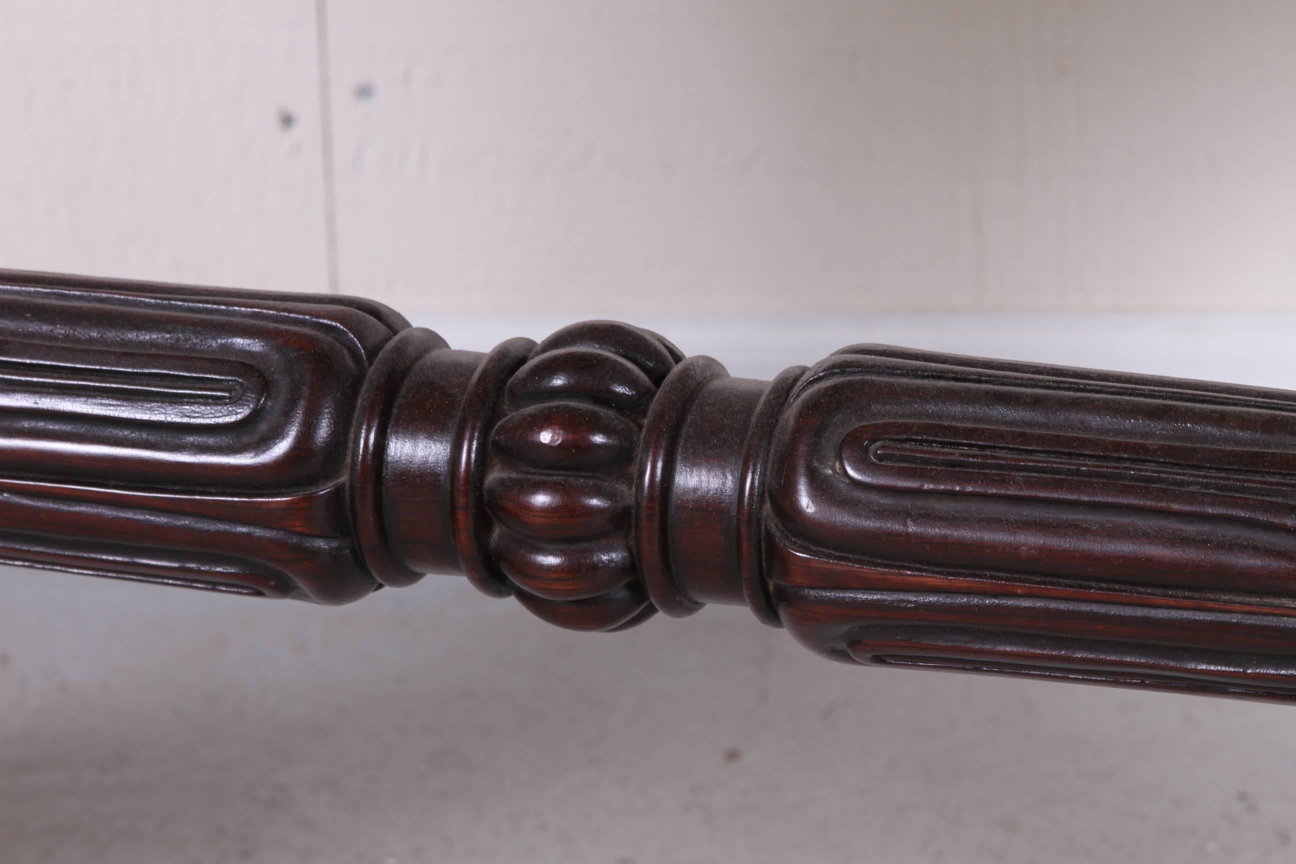 Rosewood with inset tooled burgundy leather top and gadrooned edge over two short drawers and having 2 faux drawers on the reverse side. Elaborately  carved supports ending in lions paw feet, connected by a turned baluster stretcher. Brass