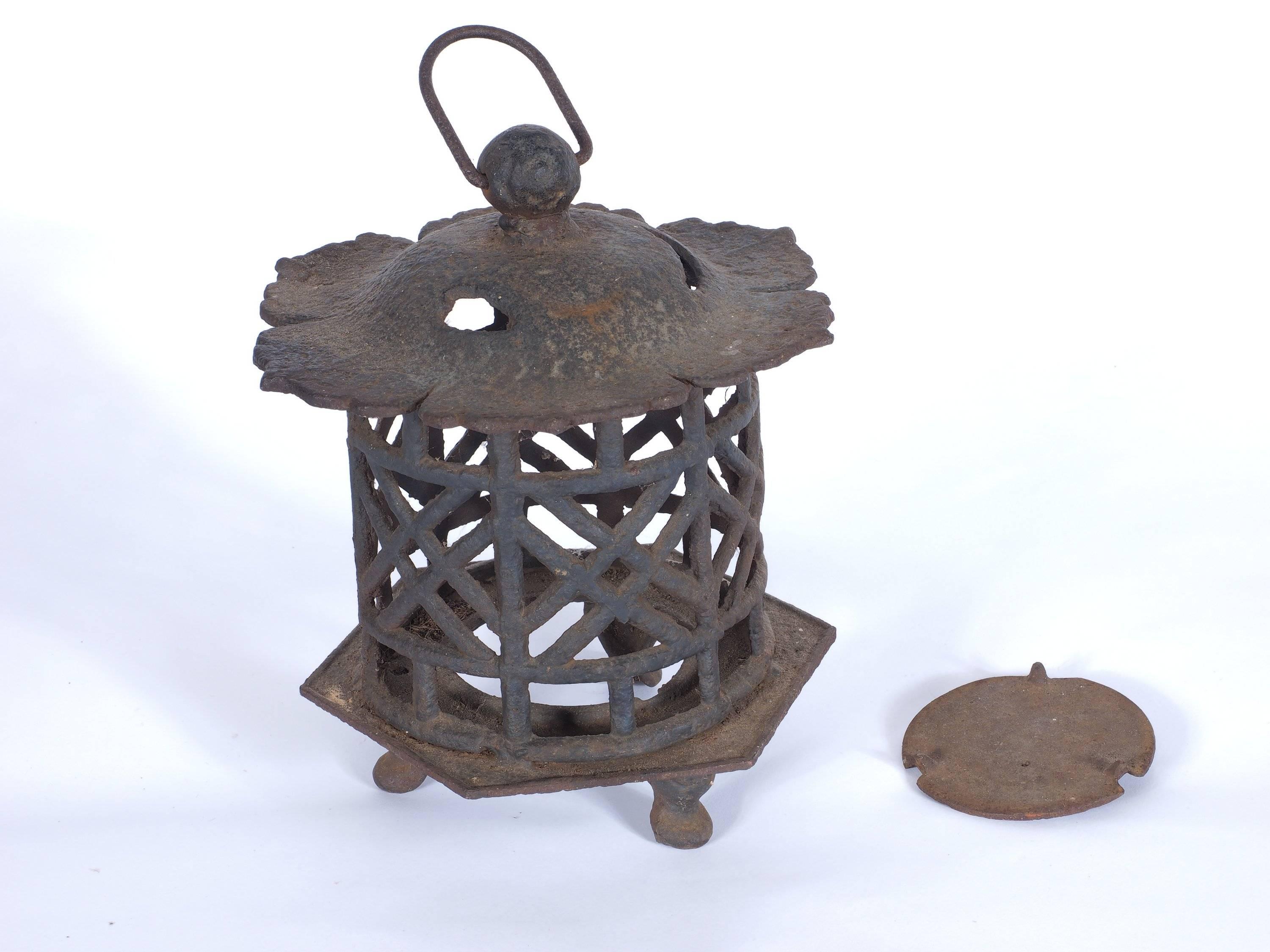 A pierced, heavy cast iron Japanese lantern on three feet with a ring for hanging. Good traditional form and condition.