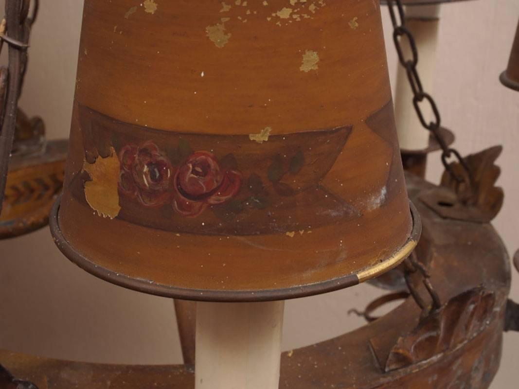 An antique toleware six-light chandelier with circular frame having six chains attaching a larger ring with urn center and scrolling arms. Mustard colored paint with burgundy banding. Appropriate wear including paint loss.