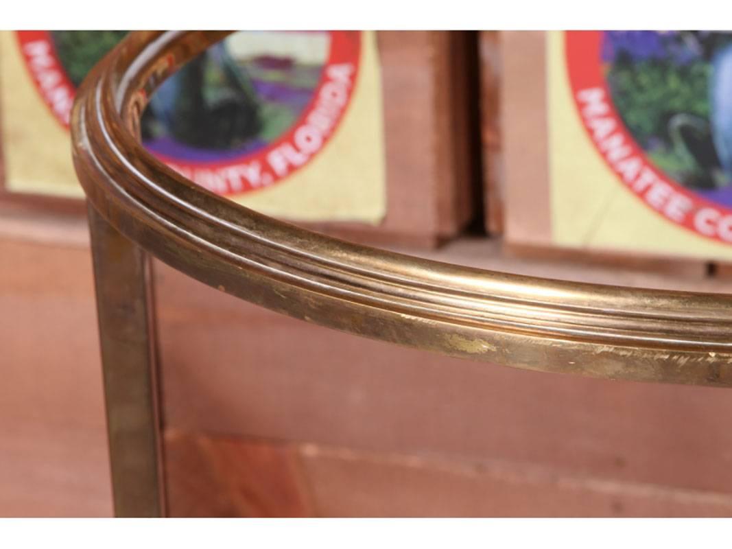 Pair of Hollywood Regency bronze tables outfitted with custom cut-glass tops, believed to be from Maison Ramsay. One table is slightly taller than the other and there is some acceptable wear on both frames. Tables have curved triangular stretcher