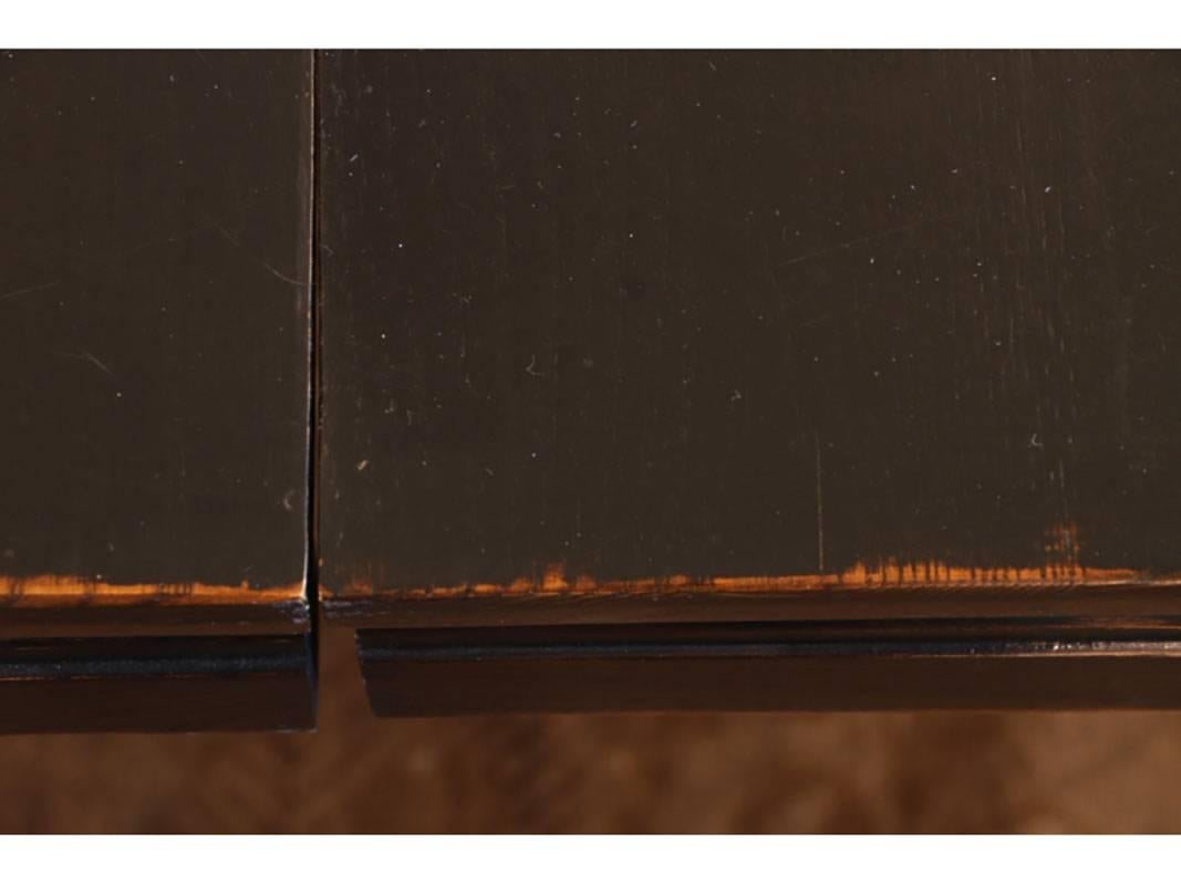 A large dining table in dark stained elmwood with inset bronze plaques with extensive Asian characters. Two leaves are included in measurement below. Eight dining chairs have slightly scrolled backs with straight legs and thick cushioned vinyl