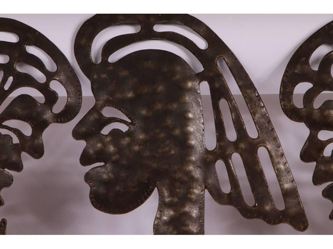 Hammered iron sculpture with two people in profile holding up a frog-like being. Signed on front, Serge Jolimeau (Haitian, B. 1952).
 