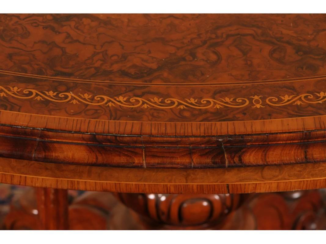 Specimen walnut with satinwood and marquetry inlaid border. The base with a centre pedestal surrounded by four turned and fluted columns. Raised on a scrolled leafy carved base. Some light scratches to top. Stamped Gillow and Co.
            