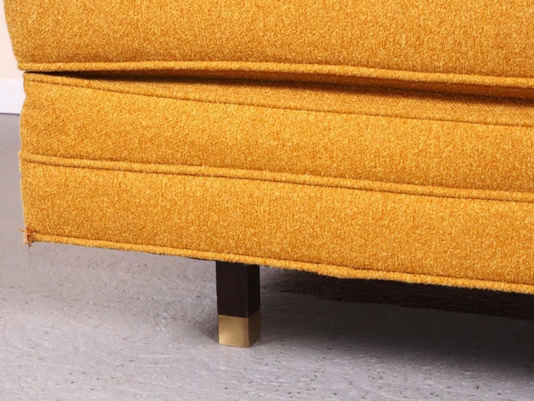 Mid-Century ottoman designed by Harvey Probber. Original upholstery in orange / yellow wool. Button tufted with clean lines and brass capped feet. Worn areas of wool noted in photos.