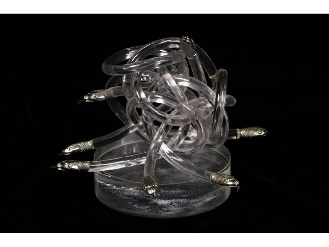 A cluster of eight inter-twined Lucite snakes having cast nickel heads with metal tongues on a round Lucite base, circa 1970s. Sculpture measures 6 3/4
