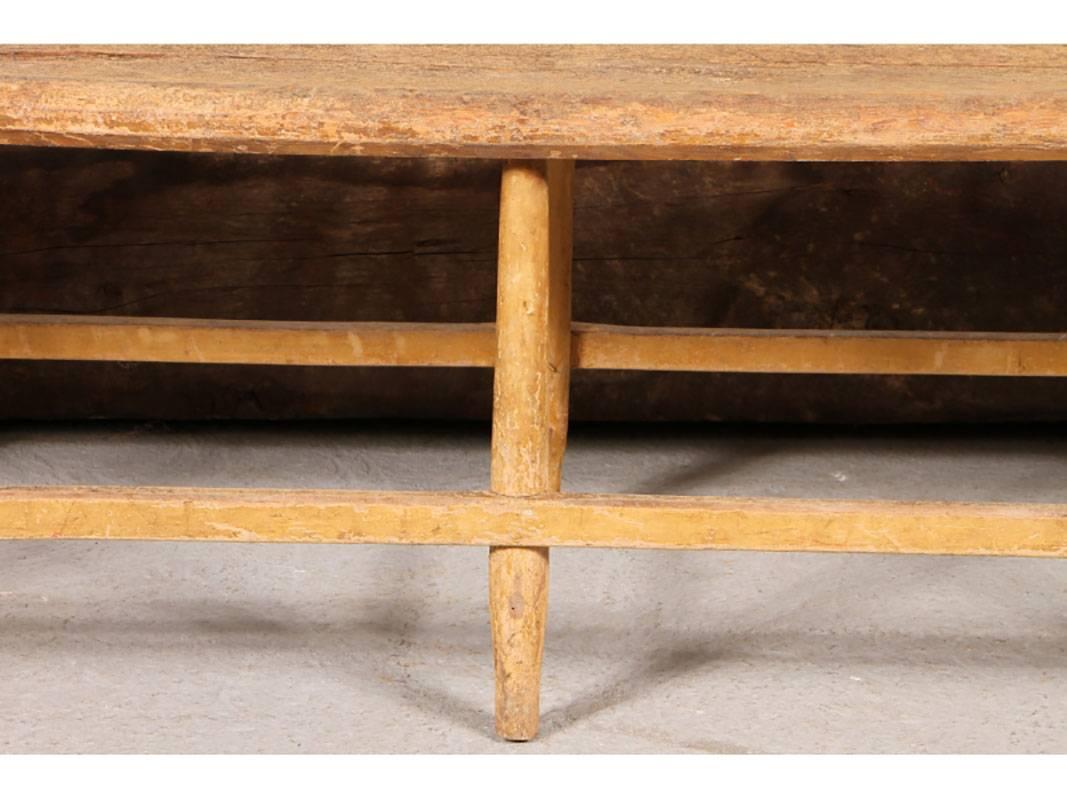 Windsor bench with spindle back, turned stretcher legs and scooped seat. In original paint decorated old chippy yellow paint with overall wear. It is fragile with dry and loose joints and unstable paint. It's best suited for a decoration rather than