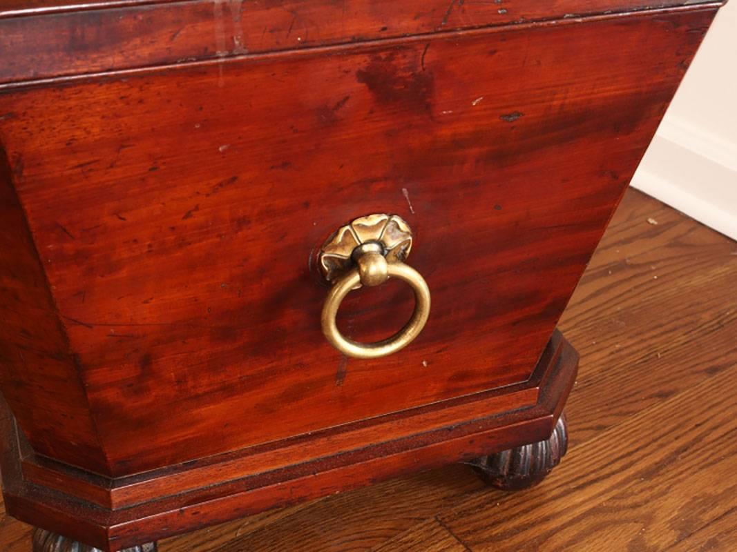 Exceptional antique wine storage chest in handsome selected flame mahogany with brass ring handles, carved dental molding resting on casters. Metal liner.