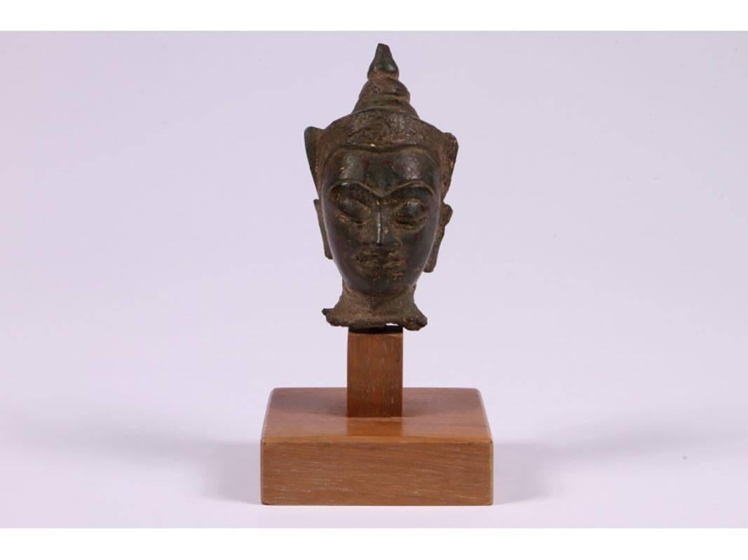 Diminutive cast bronze or iron head of a deity mounted on a plinth wood base.
Condition: consistent with age.