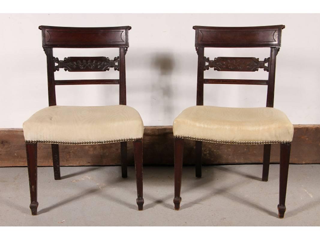 Side chairs circa 1830 having curved rectangular crest rails over conforming horizontal splats with carved vining decorations. The oversized tight upholstered seats raised on square taping legs and terminating on spade feet.
Condition: Some with